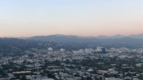 Horizonte-De-La-Ciudad-Al-Atardecer-En-Los-ángeles-Con-Montañas-En-El-Fondo-Moviéndose-A-La-Izquierda-Sobre-La-Ciudad