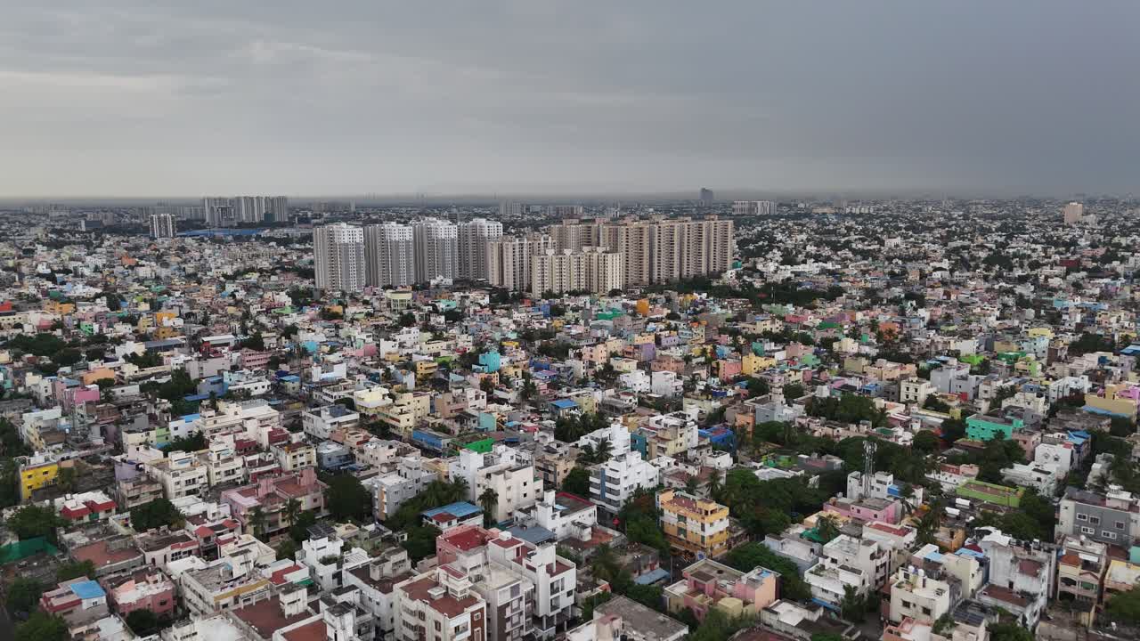 Aerial footage of a sprawling, densely populated metropolitan city. moving perspective, capturing the dynamic urban landscape under the dramatic, overcast skies of the rainy season, from hazy daytime