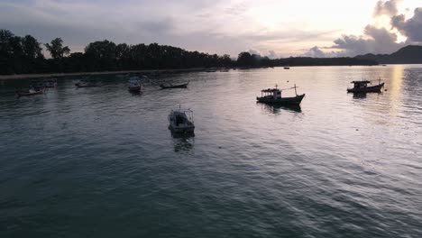 Drone-aerial-slow-move-parallax-over-tropical-blue-water-during-sunrise-with-thai-speedboats-around