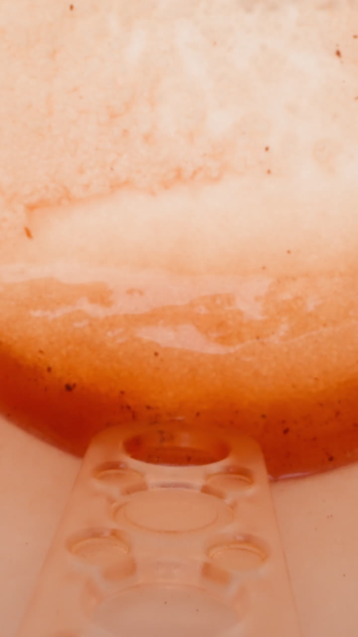 Fallen on side paper cup with plastic stick and leftovers of sweet tea on wooden table macro view. Rubbish in street cafe. Disposable dish for beverages