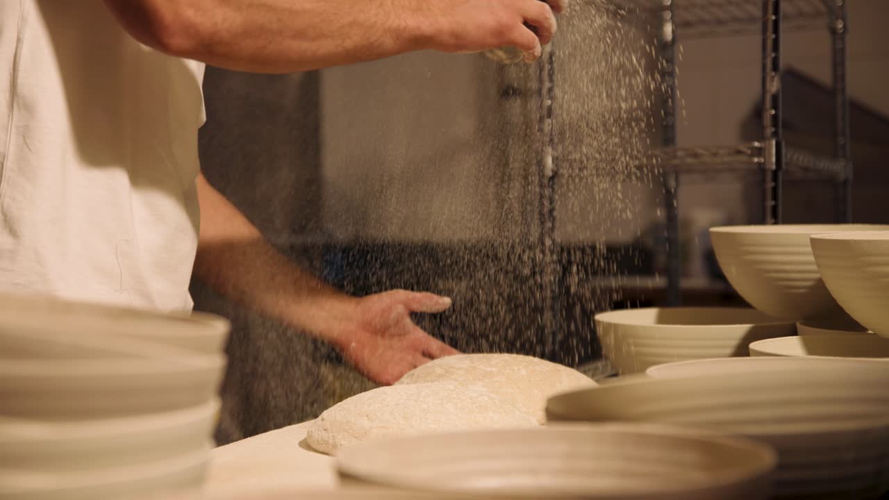 Baker Sprinkling Flour on Dough in a Commercial Kitchen