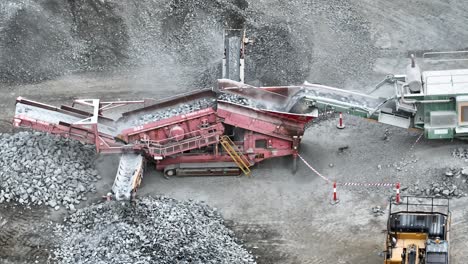 aerial panning shot of excavator placing rocks into conveyor belt sorting machine