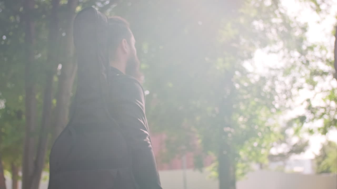 Musician with Guitar Case Walking in Park