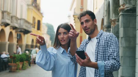 young happy romantic couple of tourist using applications on a smartphone for checking new places to visit together while sightseeing  in old city center during holidays trip.