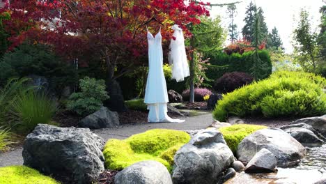 Captivating-aerial-view-of-a-wedding-dress-hanging-gracefully-from-a-tree,-amidst-a-picturesque-outdoor-setting