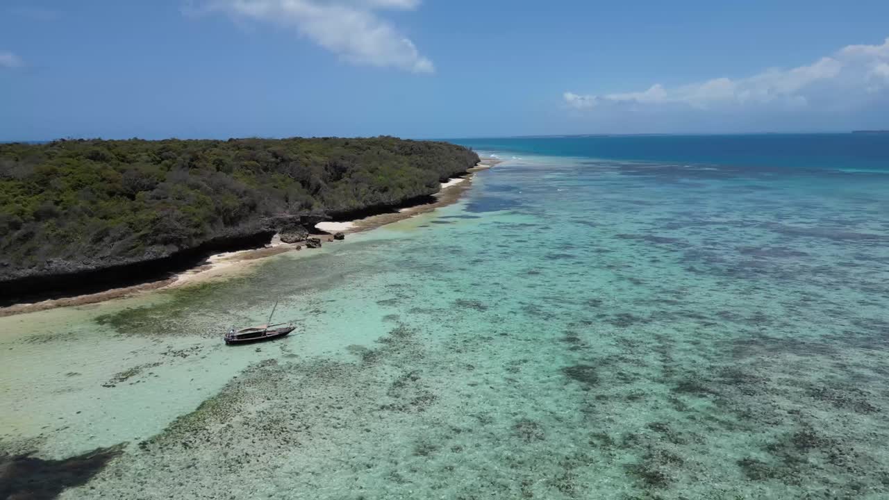 Sailboat floating above the shallow coral lagoon in Pungume Island Tanzania Africa southern Zanzibar, Aerial right rising shot