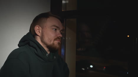 man looking out window at night