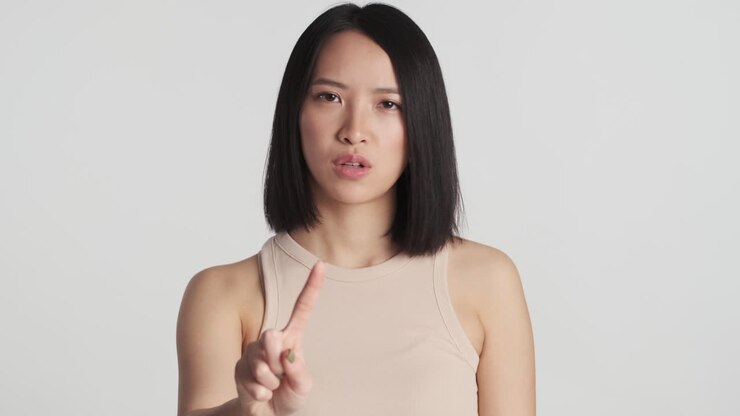 Asian woman waving no with the head on camera.