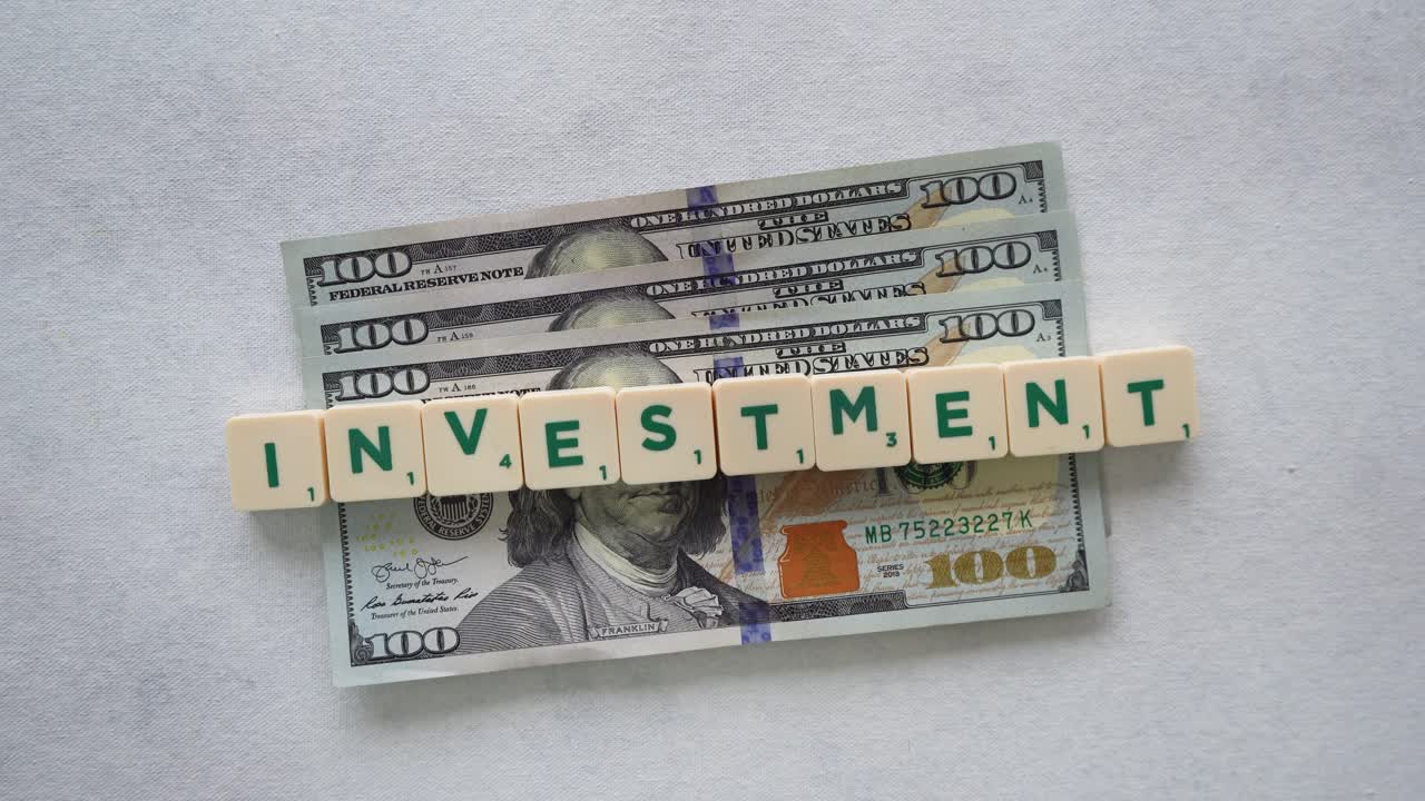 Word &amp;quot;investment&amp;quot; with green letters over a $100 dollars bills