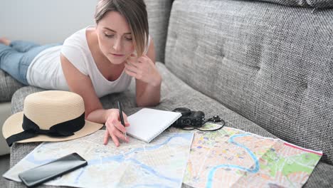 happy woman planning vacation travel trip at home after end of pandemic and quarantine. girl looking at a map writes information to a notebook.