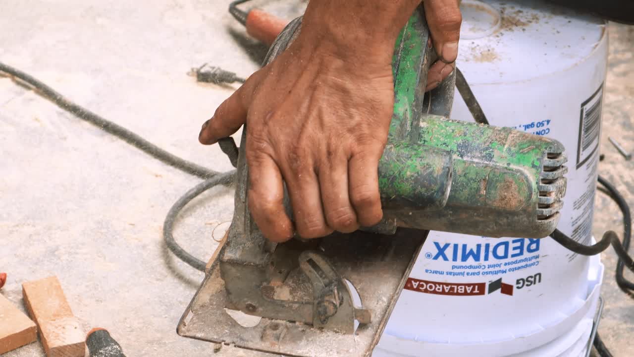 Close up view of carpenter performing skillfully a long cut into a piece of wood with his industrial circular saw machine which he uses often in his small business elaborating professional forniture