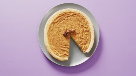 video of pumpkin pie with spices on plate on purple background