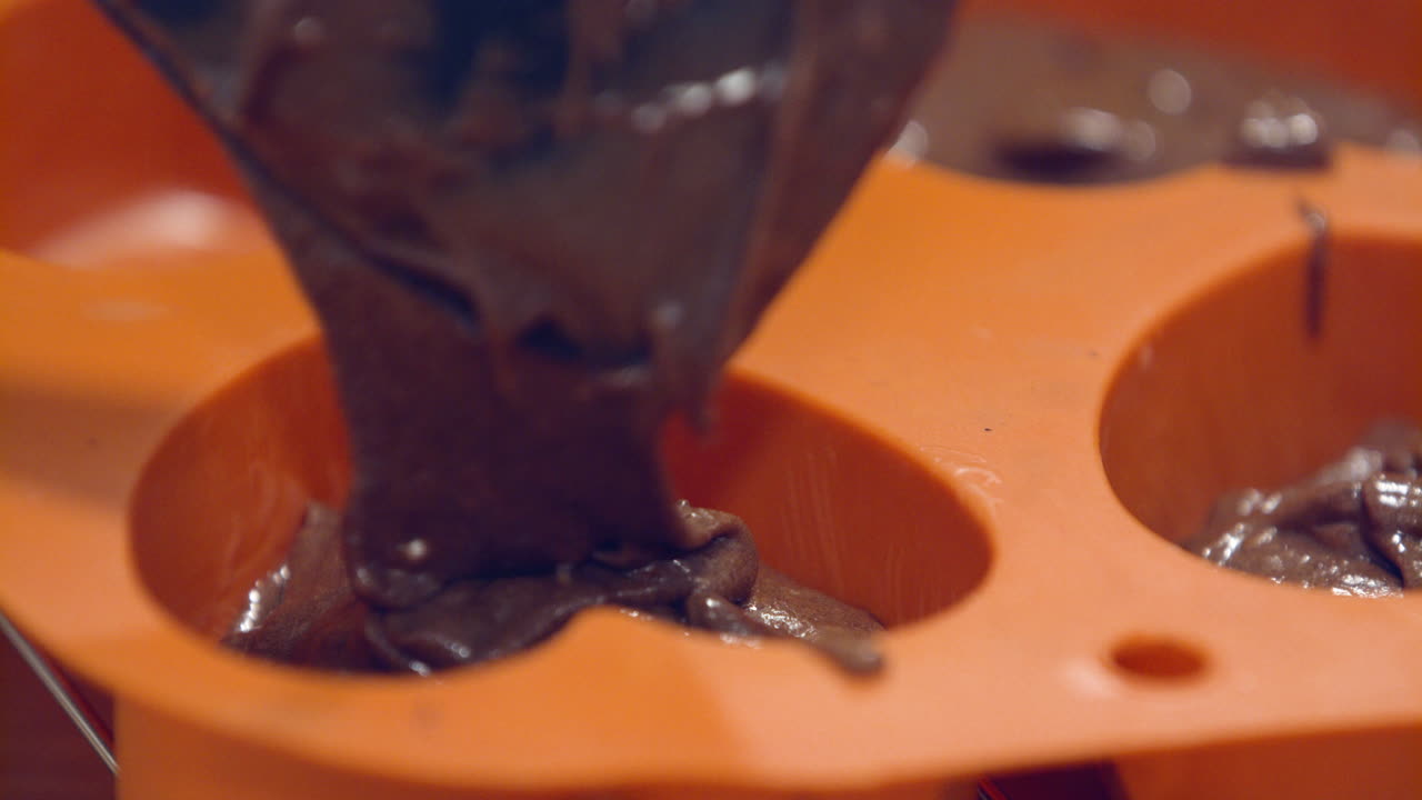 Riempimento di miscela di cioccolato in uno stampo a forma di cuore arancione - Primo piano