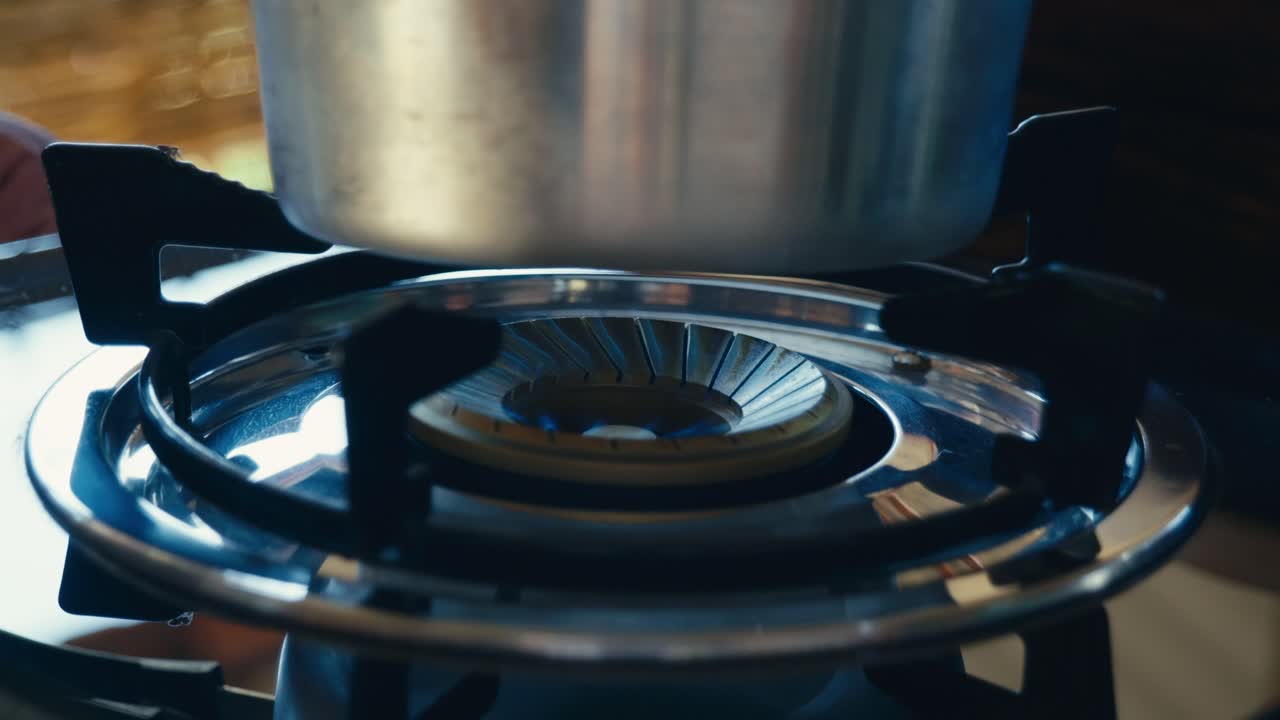 Un fornello a gas che si accende con una fiamma visibile, segnalando l'inizio della cottura in cucina e mettendo in evidenza la preparazione quotidiana del cibo
