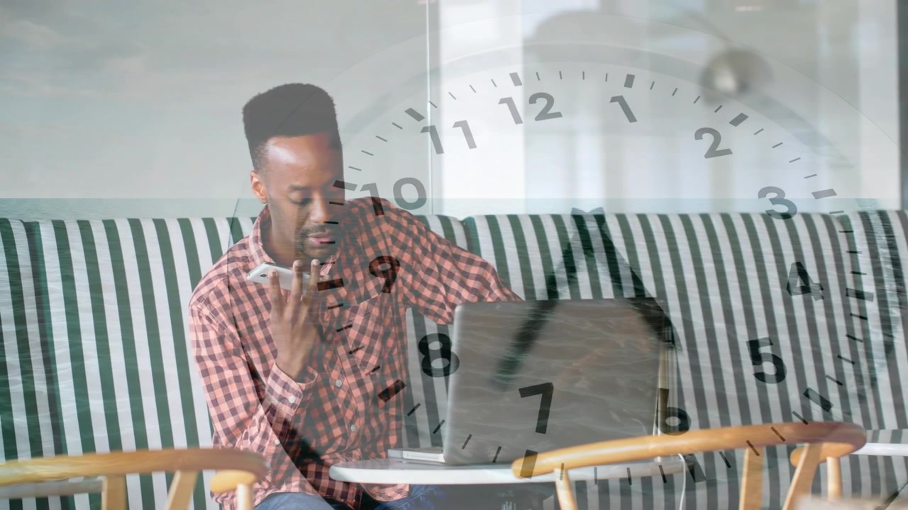 Man smiling at phone speaking into phone while checking business laptop, clock overlay showing time