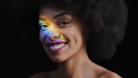 retrato multicolor de cerca hermosa mujer afroamericana con afro disfrutando de una piel suave y saludable con aspecto confiado belleza natural luz colorida sobre fondo negro concepto de cuidado de la piel
