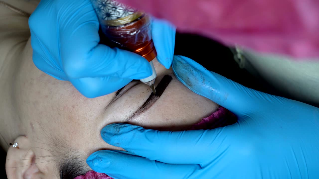 un close-up del procedimiento de microblading. una cosmetóloga profesional hace maquillaje permanente a la chica en el salón de belleza. 4k. 25 fps.