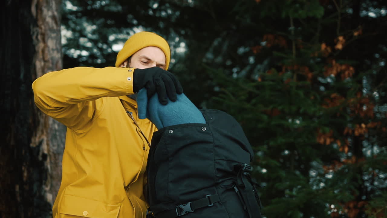 Man Packing Backpack in Forest