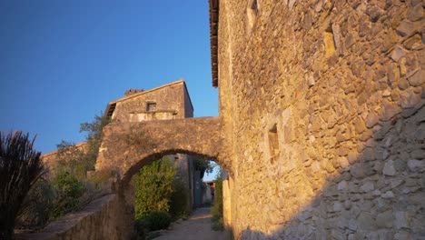 Calle-Estrecha-De-Un-Antiguo-Pueblo-Francés-Con-Un-Arco-De-Piedra-Al-Atardecer-En-Cámara-Lenta