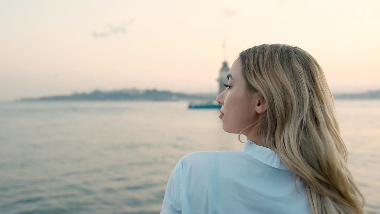 hermosa chica disfruta de la vista del atardecer del bósforo con vista de la torre de la doncella al fondo en estambul