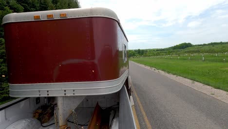 camioneta tira de un remolque de caballos en la carretera del campo rápido, vista posterior del punto de vista