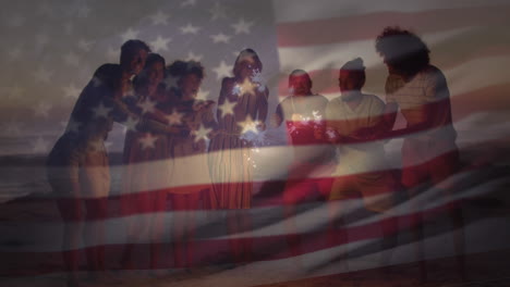 american flag waving against group of friends enjoying with sparklers at the beach