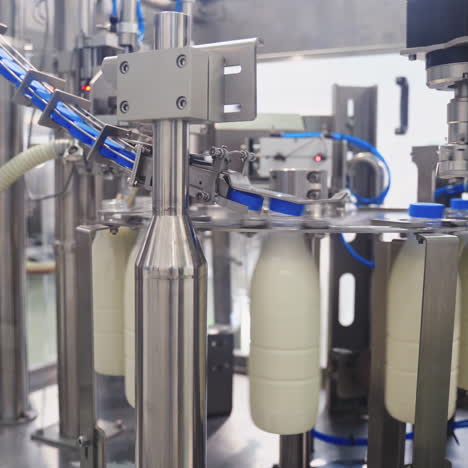 robotic dairy plant indoors. automatic equipment for covering plastic bottles with milk in a modern factory. process of putting plastic lids on bottles.