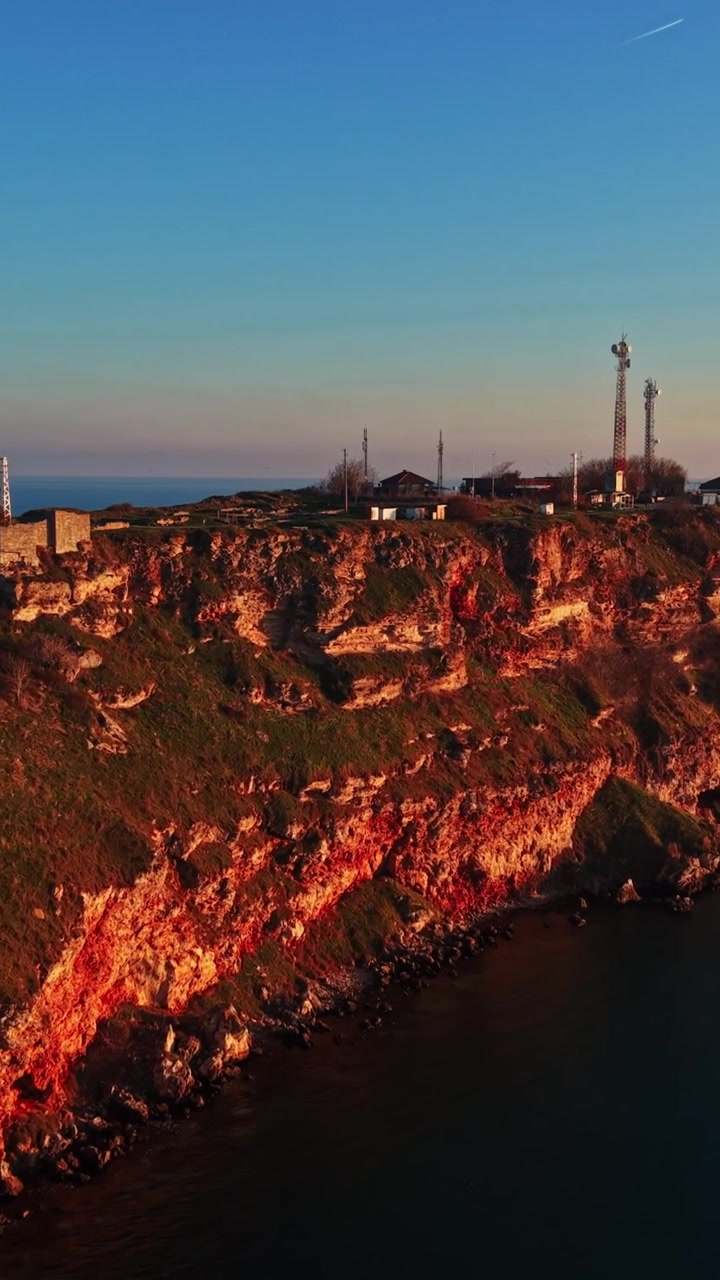 Splendida vista costiera al tramonto con scogliere e acqua dell'oceano a fuoco