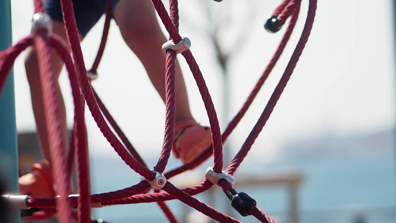 Child's Feet Climbing on Red Rope Playground Structure