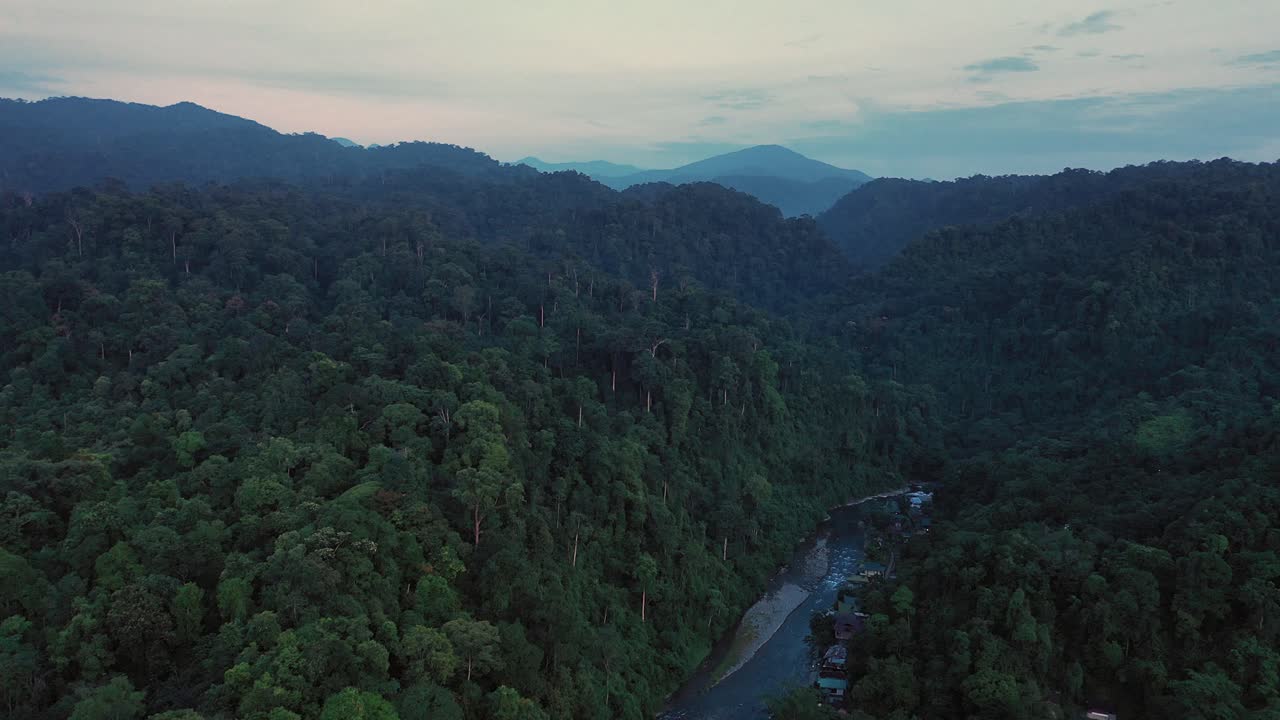 Cinematic aerial view of Bahorok River and jungle scenery from Bukit Lawang village in Gunung Leuser National Park, the Tropical Rainforest Heritage of Sumatra, Indonesia at dawn