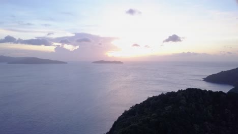 aerial view of bright sunrise and small clouds on blue sky above seascape with islands in asia