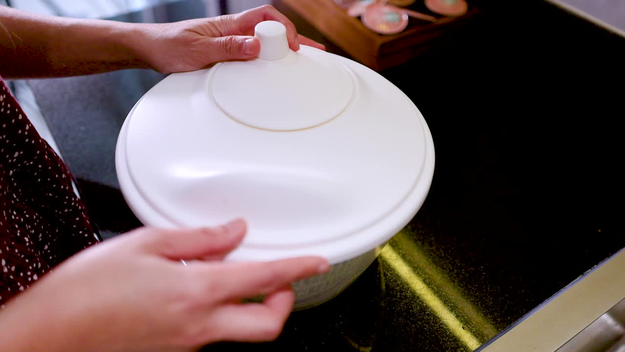 Close-up shot of hands placing lettuce into a white spinner and pressing the pump mechanism