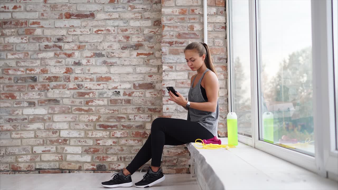 Woman resting and looking at her phone after a workout