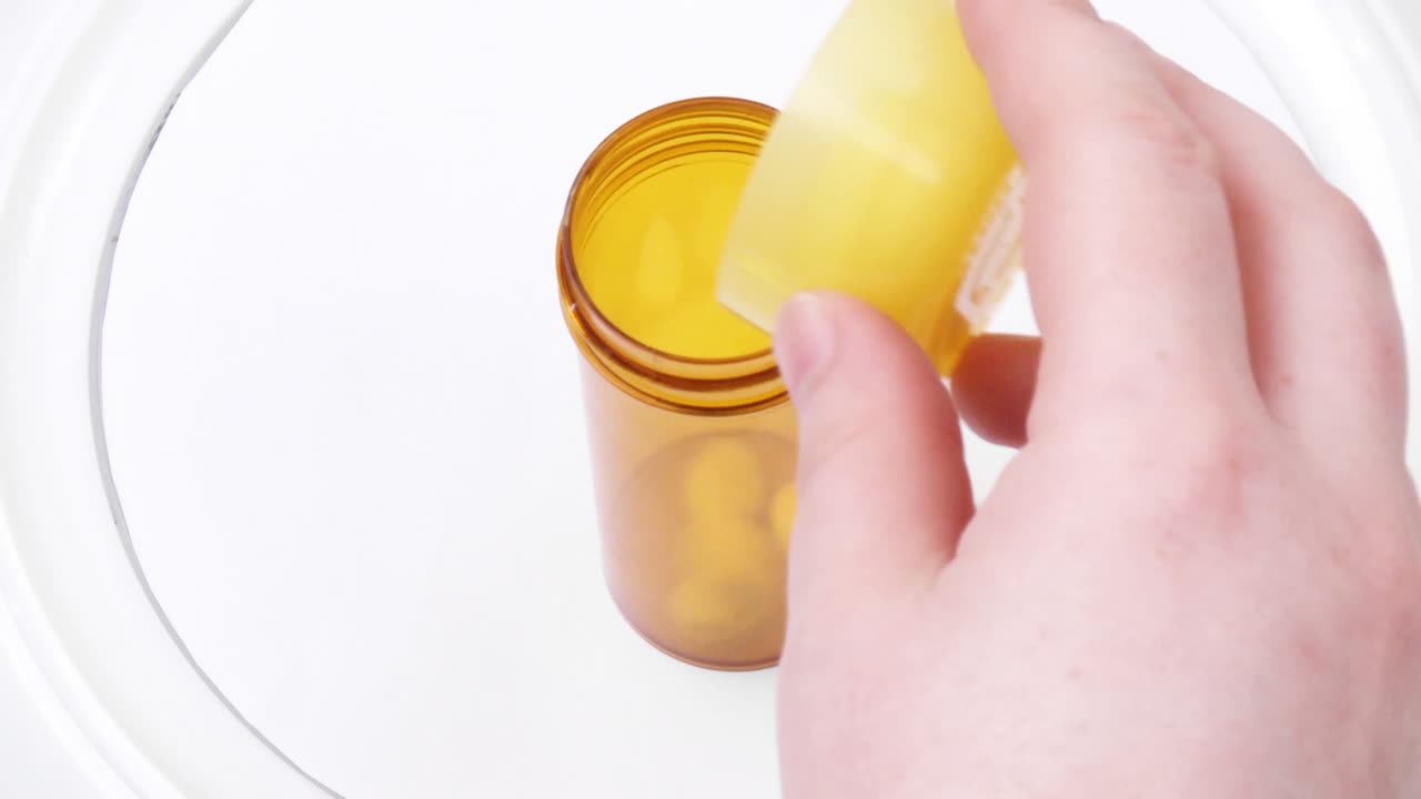alta vista de una mano arrojando pastillas en una pequeña botella