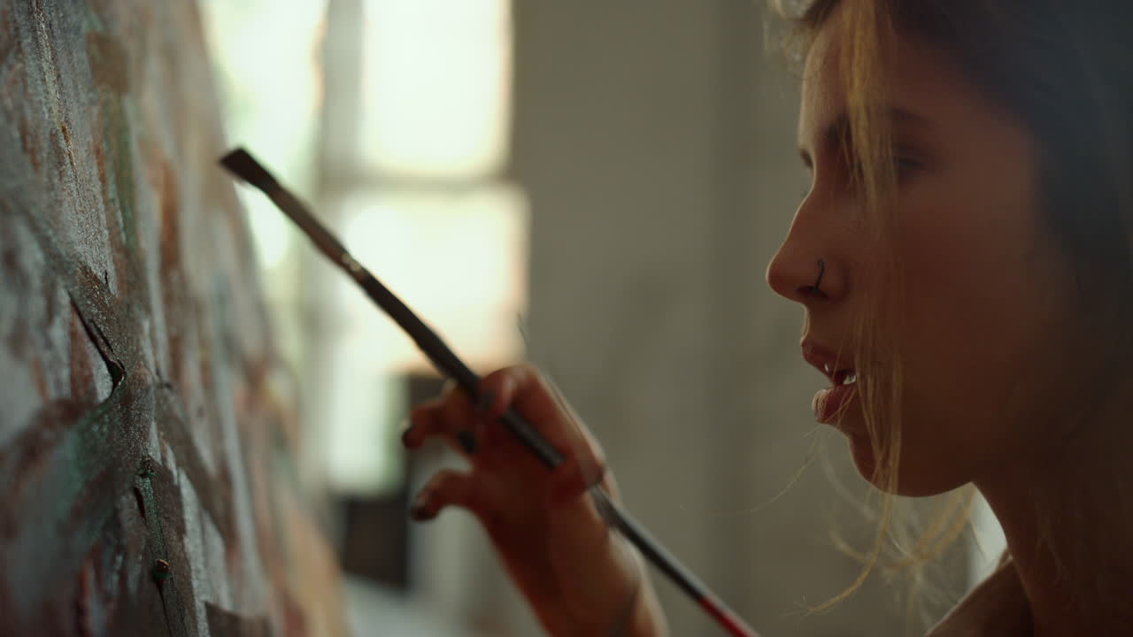 un pittore creativo che fa pennellate all'interno. una ragazza ispirata che prende un pennello.