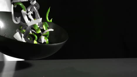 chef tossing wok of peppers in black and white