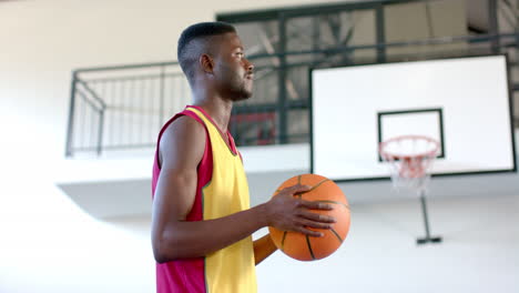 African-American-man-holds-a-basketball-in-a-gym