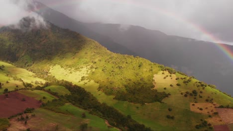 scenic aerial view of a double rainbow gracing hillside and mountainous landscape in ecuador