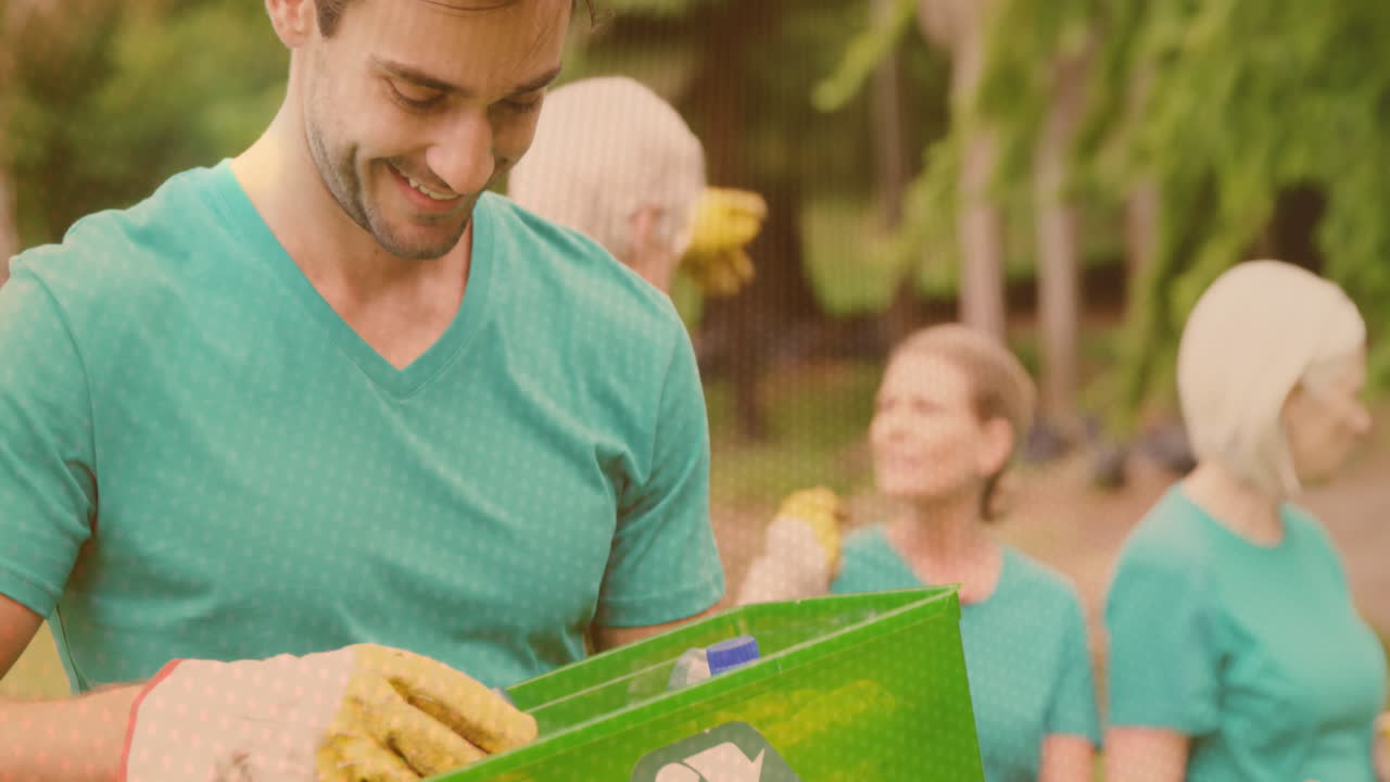 video de luces sobre un hombre caucásico feliz reciclando con voluntarios en el campo