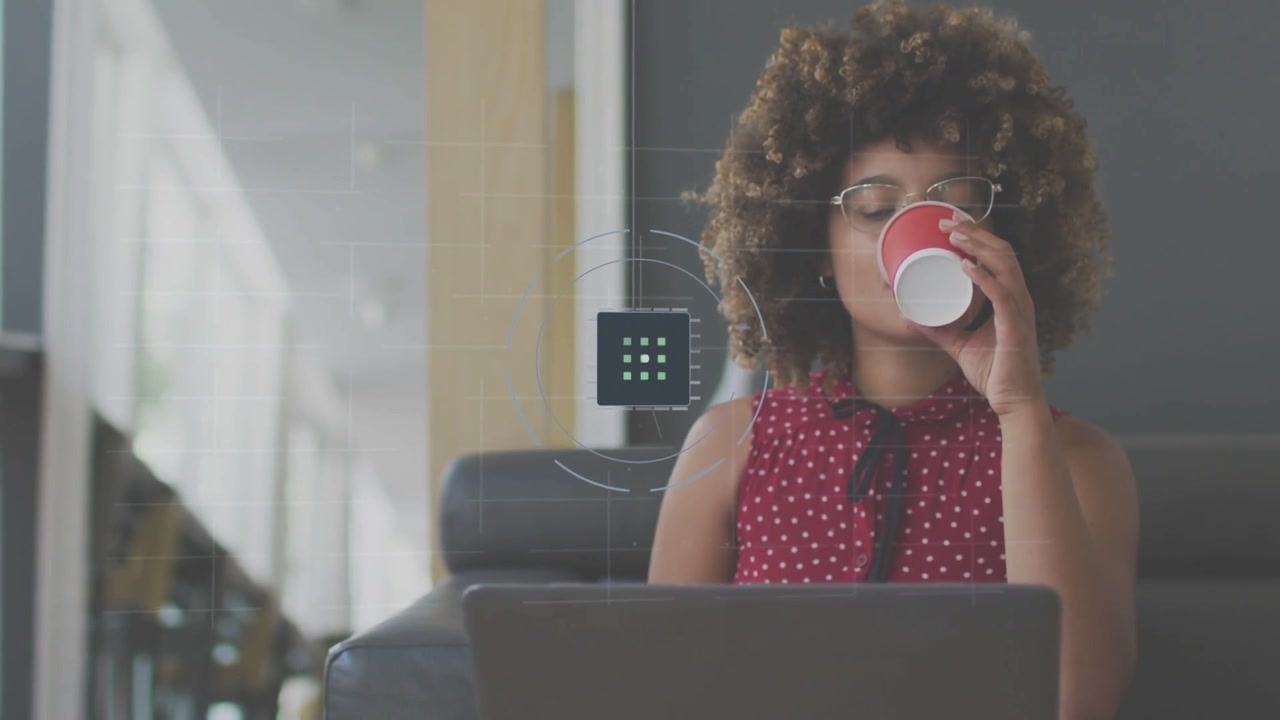 Una donna sorseggia da una tazza mentre guarda il laptop, attivando un HUD animato che si espande per supportare il lavoro tecnologico.