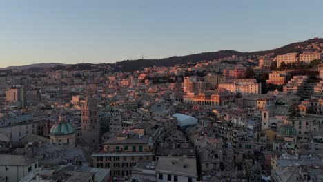 Vista-De-La-Hora-Dorada-Del-Centro-Histórico-De-Génova-Con-Densos-Edificios-Y-Colinas-Al-Fondo,-Aérea