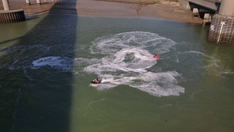 a pair of jetski race around each other at the swale on the middle of kingsferry bridge and sheppey crossing