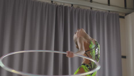 niña joven en leotardo practicando gimnasia rítmica con un anillo en un estudio 2