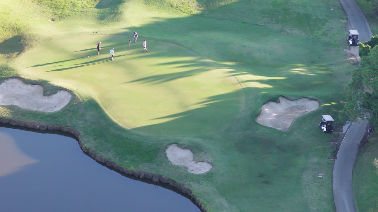 Drone captures golfers on a lush green fairway during golden hour at a scenic Gold Coast golf course