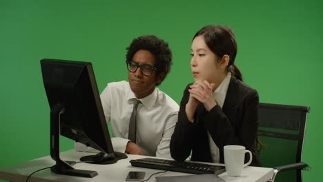 dos colegas se ven preocupados por la computadora en la pantalla verde