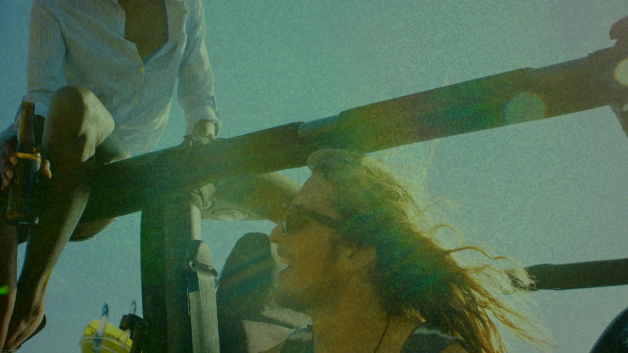 Woman turning head after breeze and camera pullback, group sharing travel moment with lens flare