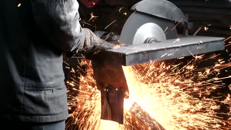 cutting of metal. closeup of the hands of men cut metal with a circular saw. sparks fly to the side.