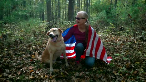 with a flag draped around them a blonde woman pets her dog and the dog looks up