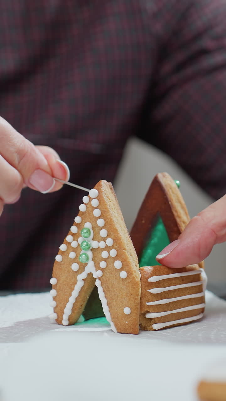 집 모양의 쿠키를 녹색과 색의 아이싱 장식으로  티슈 페이퍼에 조정하고, 더 많은 세부 사항을 준비하고, 복잡한 쿠키 디자인과 창의성을 보여줍니다.