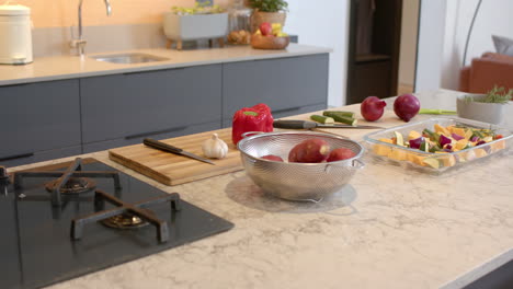 preparing vegetables on kitchen counter with cutting board, knife, and colander, at home